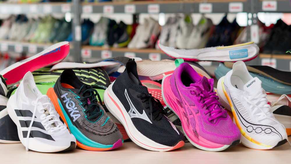 A lineup of running shoes displayed with other running shoes in the background.