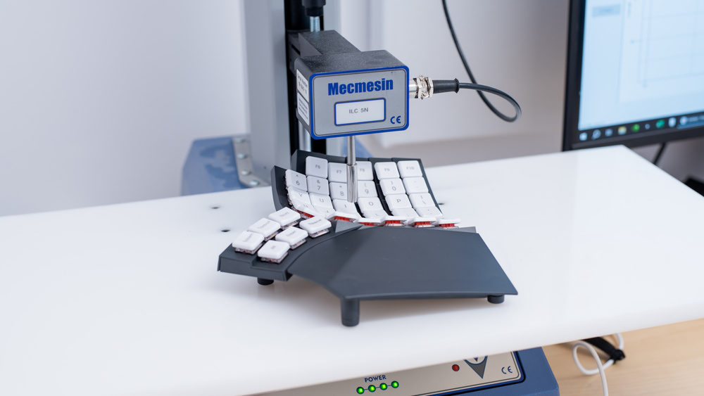 The Mecmesin force testing machine uses a plunger to accurately and consistently depress a key and extract its characteristics, such as actuation force, pre-travel, and total travel distance.