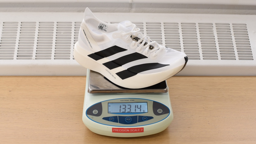 An adidas Adizero Adios Pro Evo 1 placed on a precision scale, showing a weight of 133.14 grams.